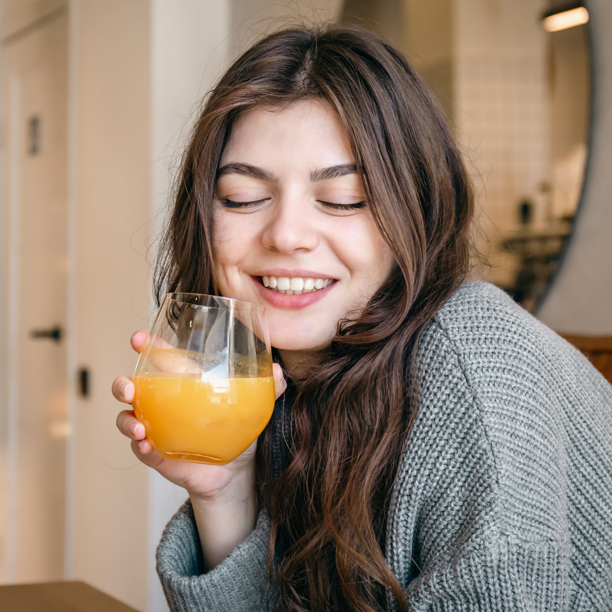 Woman holding a glass of sea buckthorn pulp juice indoors