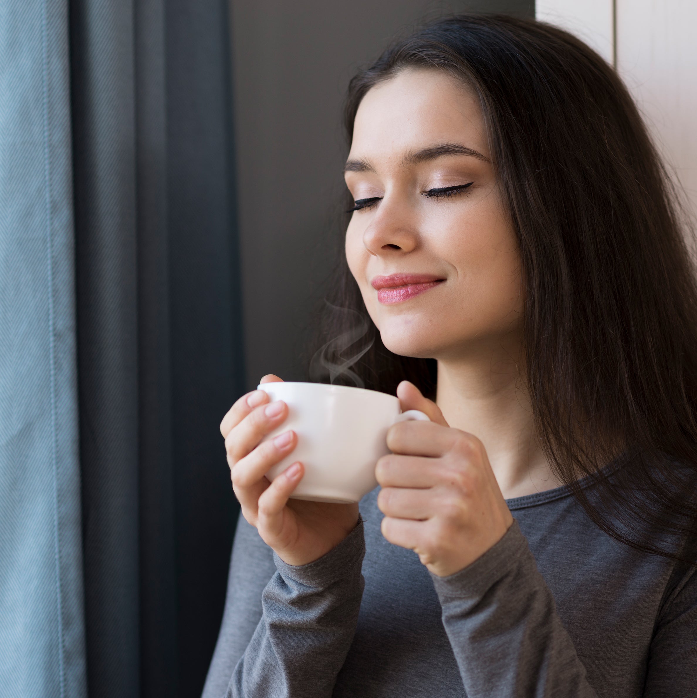 Woman holding a white mug, possibly enjoying omega ctc tea indoors.
