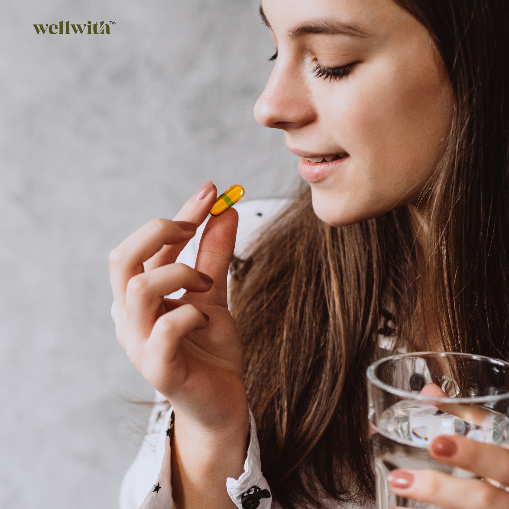 Woman holding a sbt oil capsule and a glass of water with 'wellwith' branding.