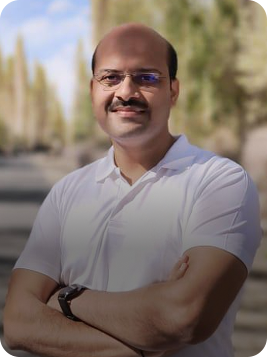 Nikhil pratap singh wearing glasses and a white shirt with a blurred outdoor background