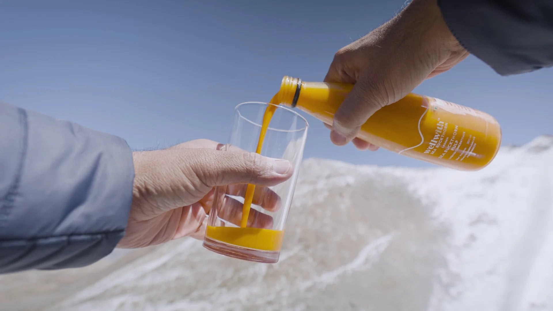 a person pouring wellwith sea buckthorn juice in a glass.